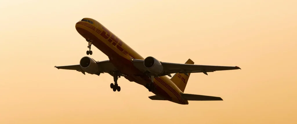 Cargo airplane flying in silhouette against a warm sunset sky.